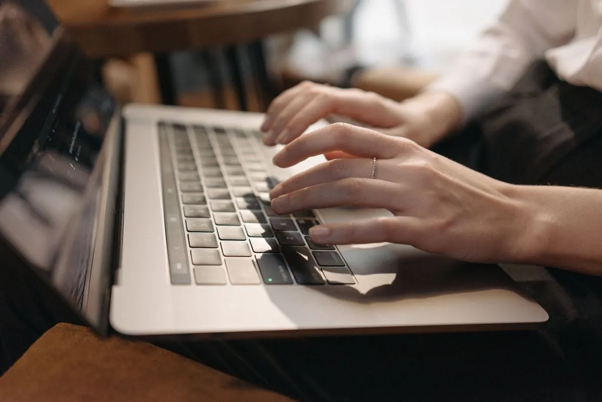 Mani sulla tastiera di un portatile con una pagina di accesso aperta a schermo