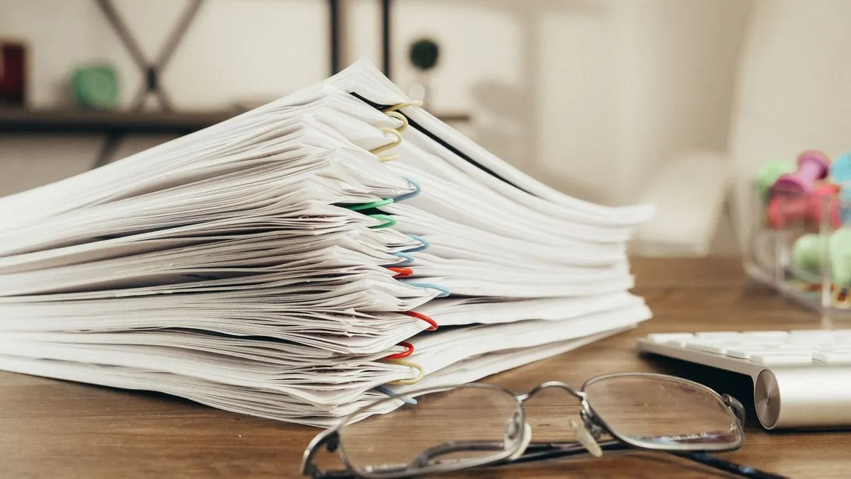 Una pila di documenti di carta accatastata di fianco alla tastiera