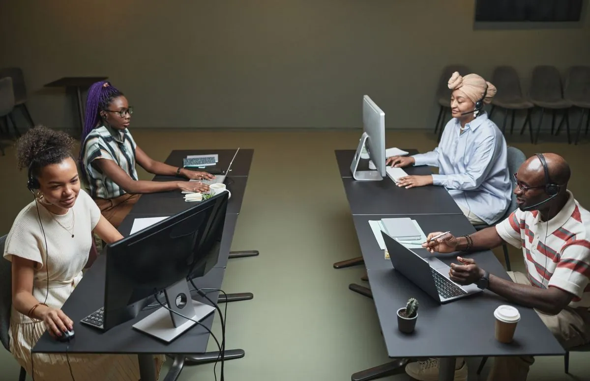 Impiegati seduti alle scrivanie con lo sguardo sui monitor accesi