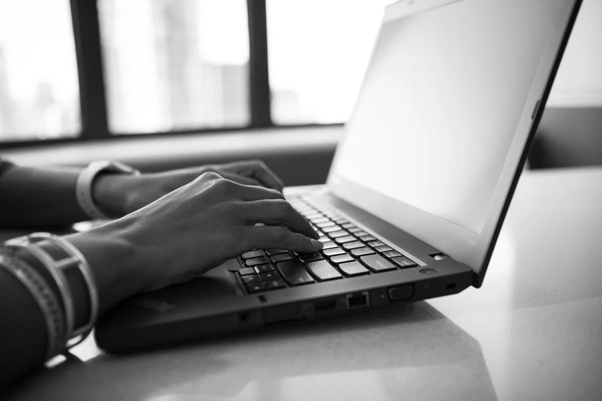 Mani che digitano sulla tastiera davanti a un modulo da compilare