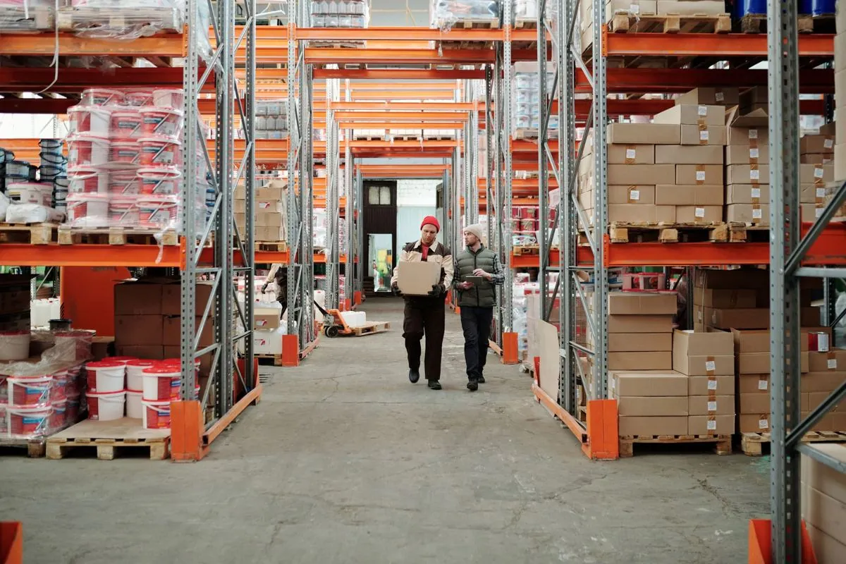 Scaffalature di magazzino con pallet e una lista di carico tenuta in mano